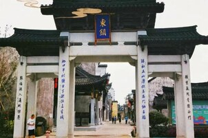Una puerta tradicional con un letrero, que da acceso a un sendero.