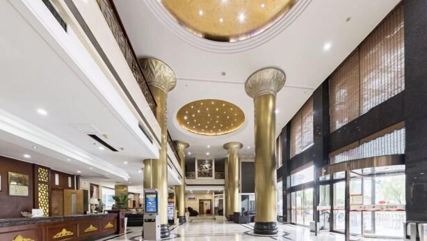 En rummelig lobby med høje lofter, store søjler og en moderne lysekrone.
