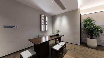 A modern room with a wooden floor, a dining table with four chairs, a potted plant, and a wall-mounted air conditioning unit.