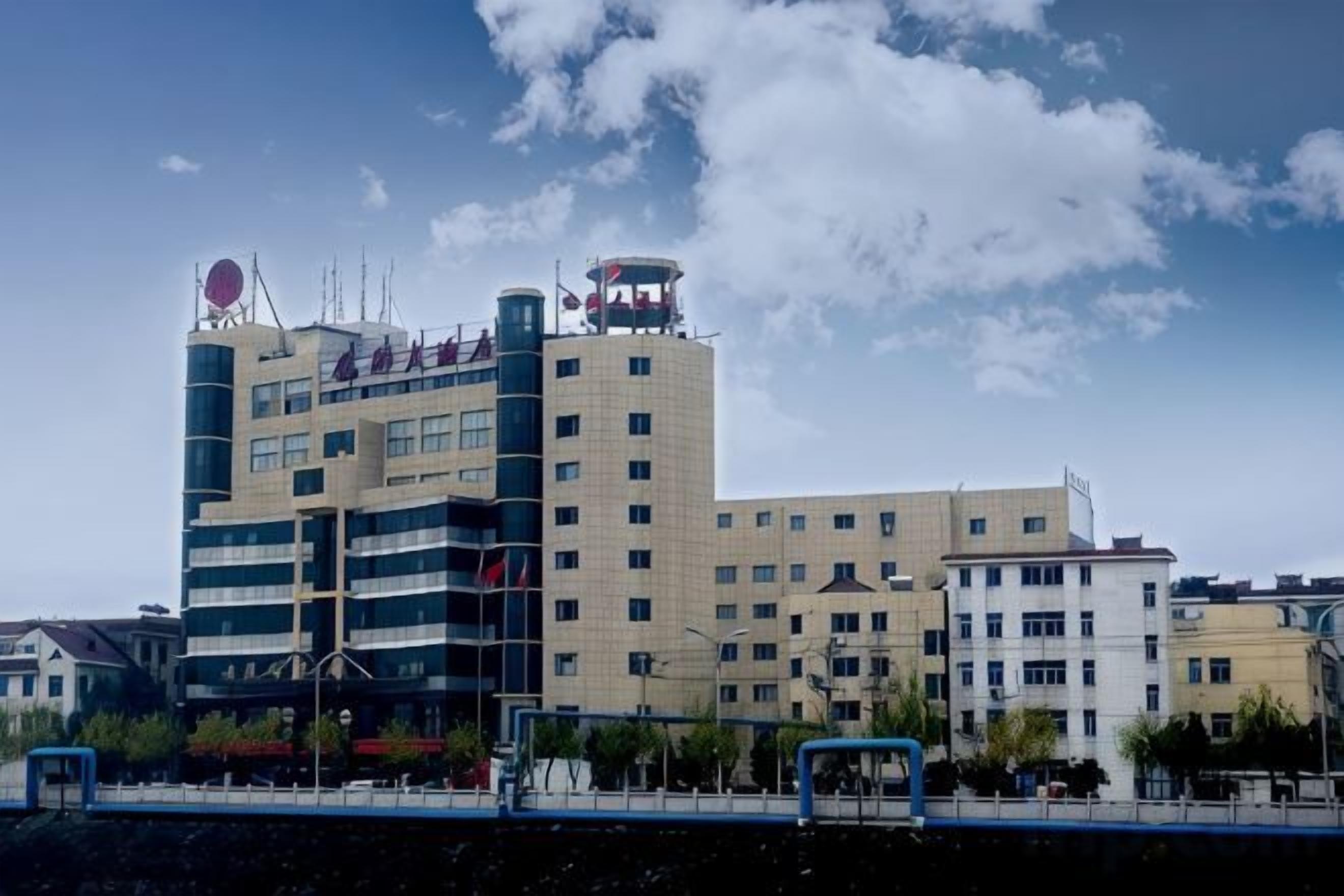A multi-story hotel with a modern architectural design, featuring a prominent circular logo on the top of the building.