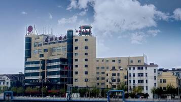 A multi-story hotel with a modern architectural design, featuring a prominent circular logo on the top of the building.