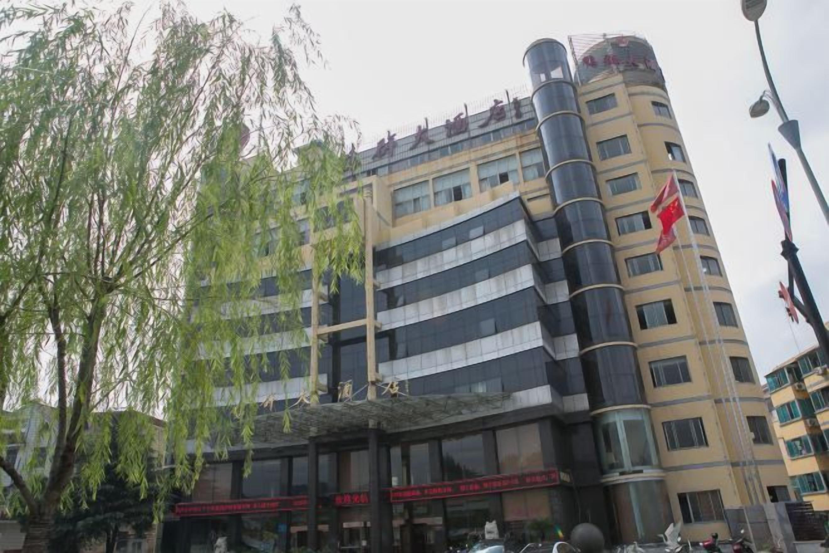 Un edificio de varios pisos con un diseño arquitectónico moderno, que destaca una estructura cilíndrica en la lateral.