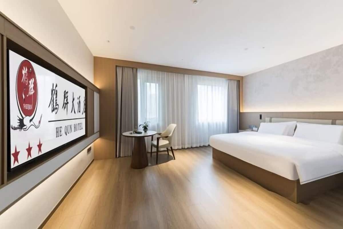 A hotel room with a bed, a desk, a chair, and a large framed sign on the wall.