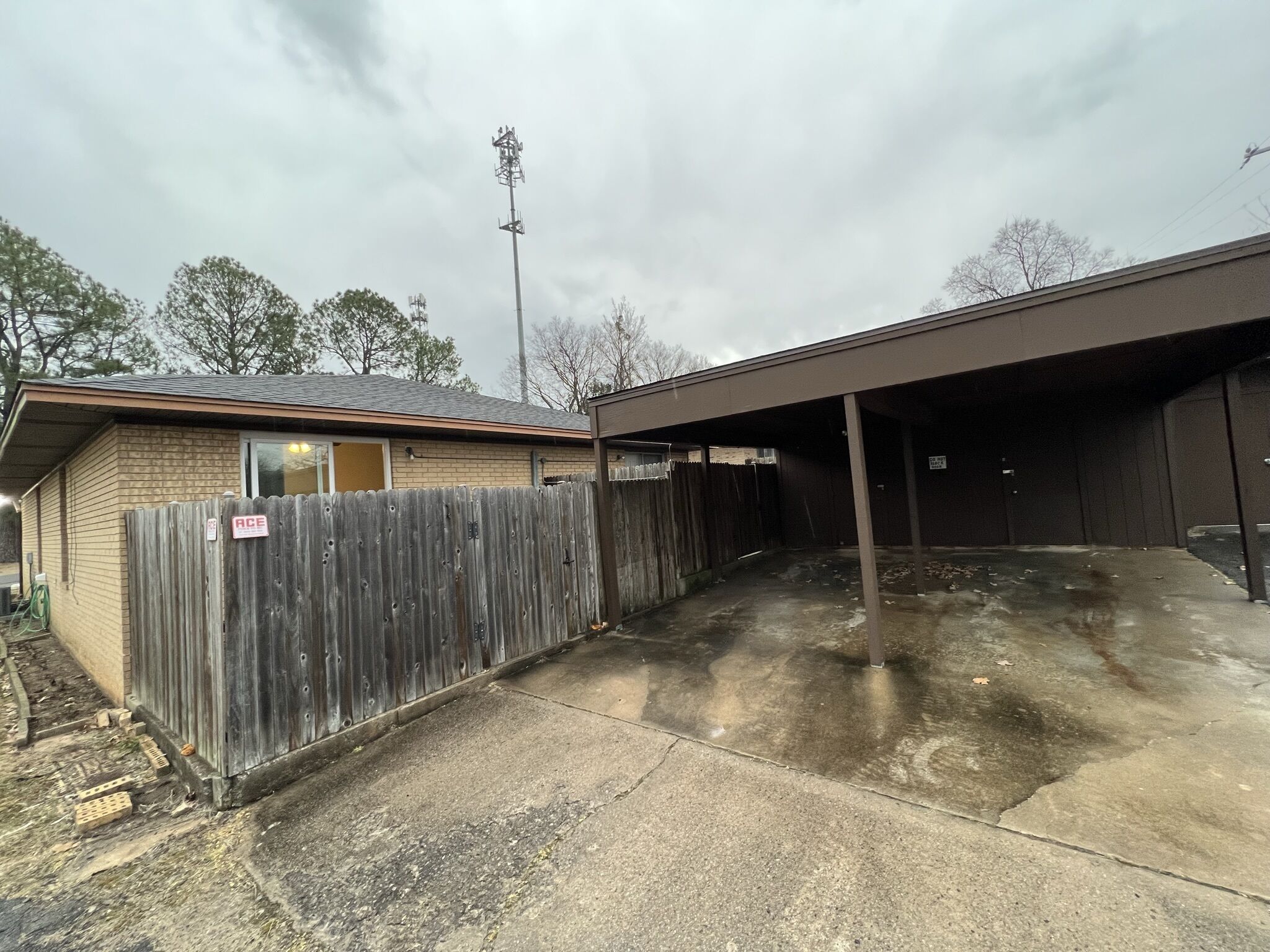 A garage with a wooden fence, a covered parking area, and a utility pole.