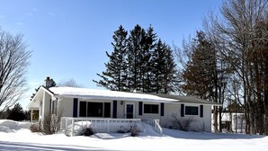 A single-story house with a covered porch and a snow-covered driveway.