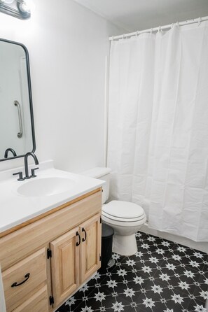 Un baño con lavamanos blanco, espejo y retrete.