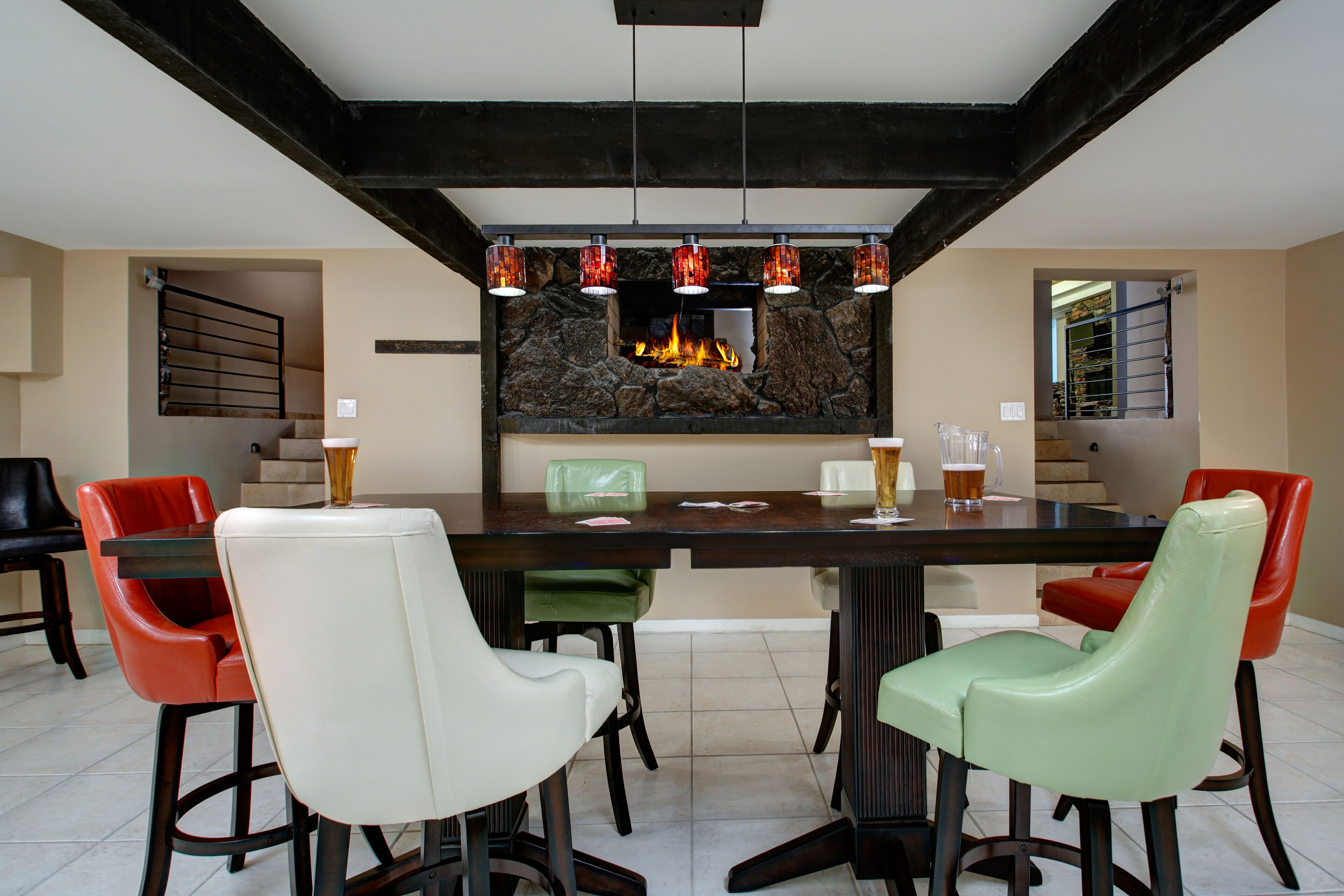 A dining area with a stone fireplace, modern chairs, and a bar.