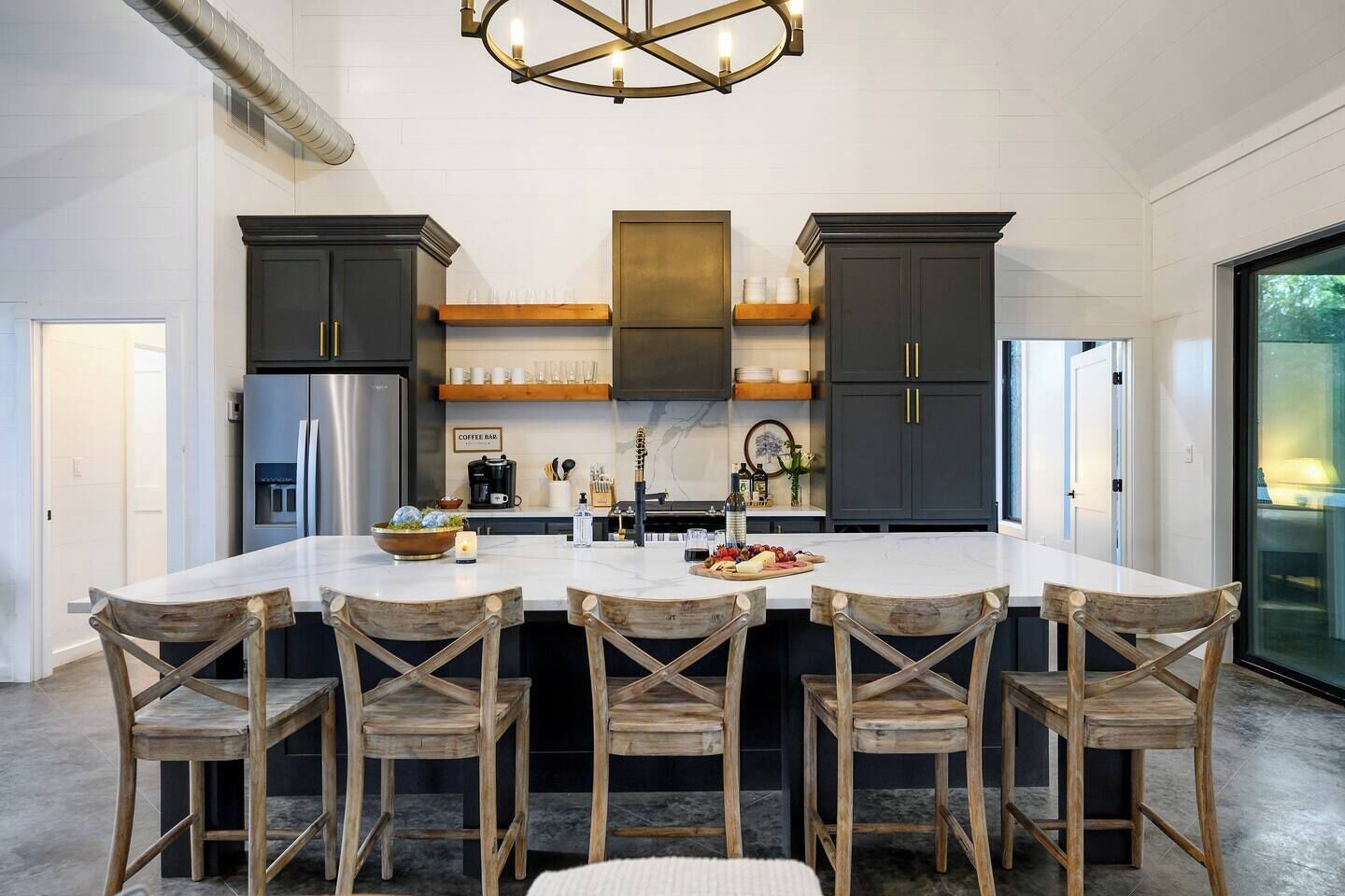 A modern kitchen with a central island, dark cabinetry, and a chandelier.