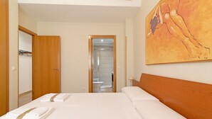A hotel room with a bed, a wooden headboard, a painting on the wall, and a bathroom visible through an open door.