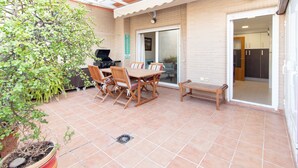 A patio with a table and chairs, a grill, and a potted plant.