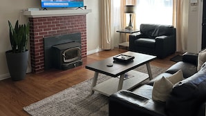 Una sala de estar con chimenea, televisor, sofá y mesa de centro.