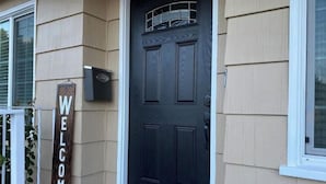 Una casa con puerta principal oscura, un letrero de bienvenida y un buzón.