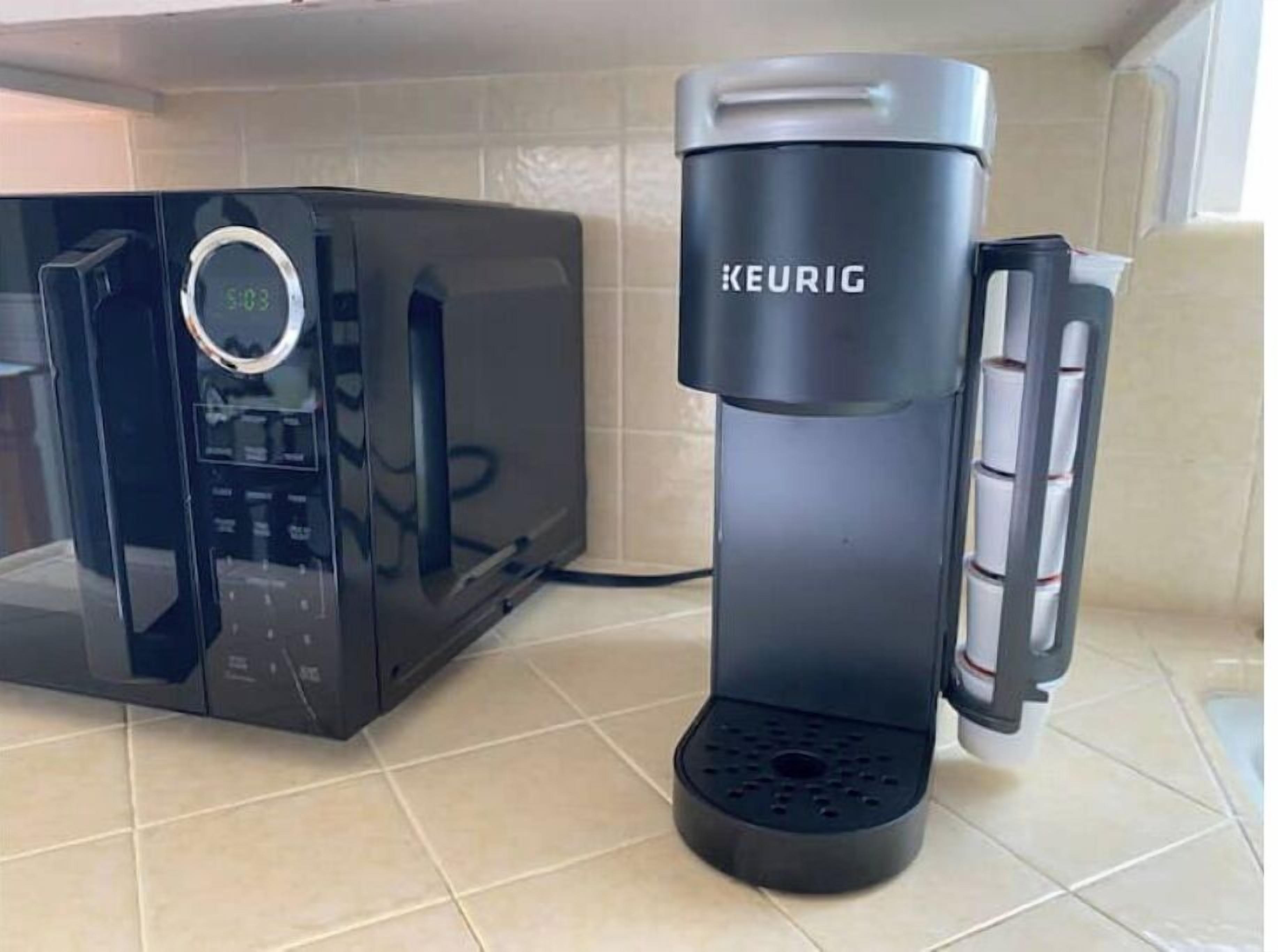 A modern kitchen with a black microwave and a Keurig coffee maker.