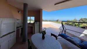 Una cocina con vista al mar, una mesa de comedor con un jarrón y un balcón con una silla.