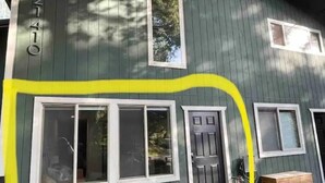 A house with a green exterior, white trim, and a number '21410' on the side.