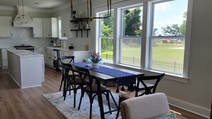 Una cocina moderna con una isla grande, armarios blancos y un comedor con mesa y sillas.