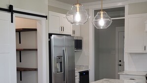 Una cocina moderna con una isla grande, armarios blancos e iluminación colgante.