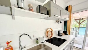 A modern kitchen with white cabinetry, a double sink, and a built-in oven. - The View – Sea View Studio in Oyster Pond (Oyster Pond)