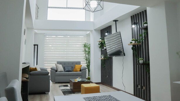 A modern living room with a grey sofa, a coffee table, and a TV mounted on the wall. - EDIFICIO CAMILA (Manizales)