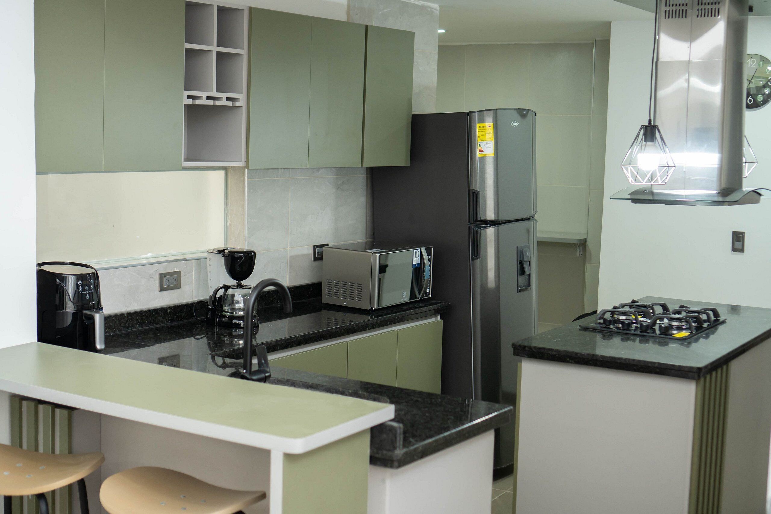 A compact kitchen with a refrigerator, microwave, gas stove, and a coffee maker.