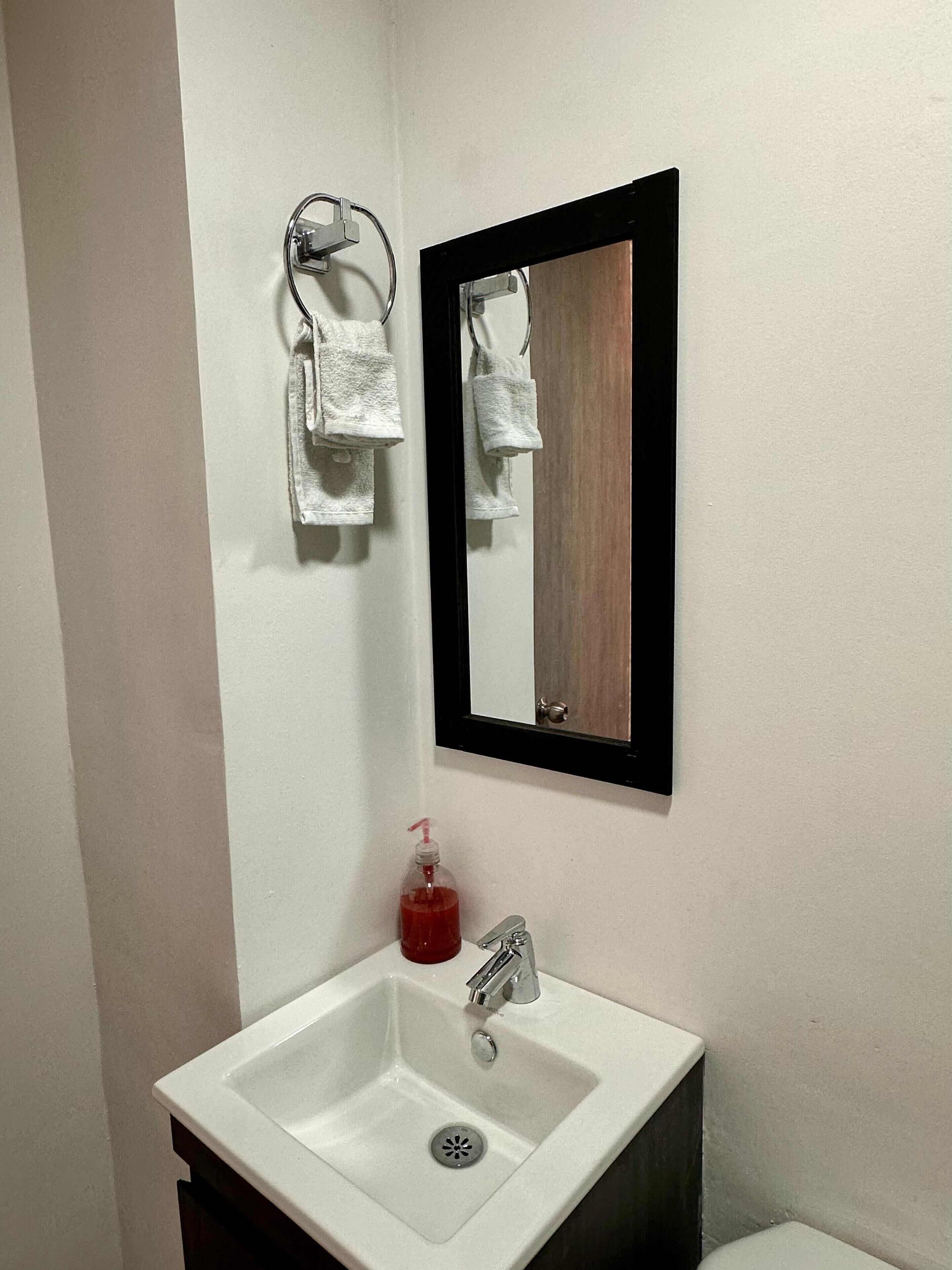 A bathroom with a white sink, a mirror, and a towel rack.
