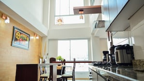 A modern kitchen with a dining area, large windows, and a view of the city. - EDIFICIO CAMILA (Manizales)