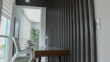Un espacio de oficina moderno con un escritorio de vidrio, una silla blanca y una planta en maceta.
