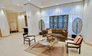 Relax in this stylish living room with a glass coffee table, armchairs, and sofa, surrounded by a large window and decorative screen.