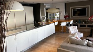 Une cuisine moderne avec des meubles blancs, un îlot central et un coin repas comprenant un canapé et des chaises.