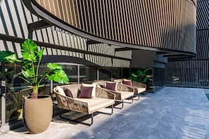 Un espace extérieur moderne, aménagé avec des meubles en osier et de grands pots de plantes.