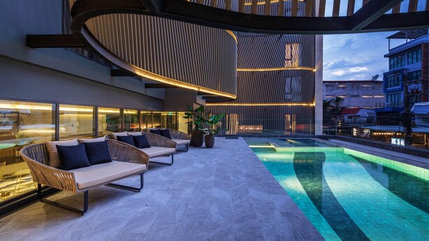 A modern outdoor lounge area with a pool, seating, and a unique architectural design. - Best Western Ratchada Hotel (Bangkok)