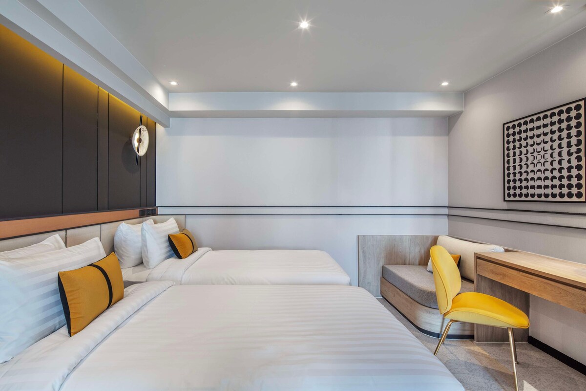 Et moderne hotelværelse med to senge, et skrivebord og en stol.