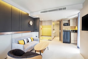 A modern living room with a sofa, a coffee table, and a seating area with a chair. - Best Western Ratchada Hotel (Bangkok)