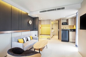 A modern living room with a sofa, a coffee table, and a seating area with a chair. - Best Western Ratchada Hotel (Bangkok)