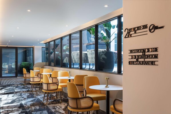 A modern interior with yellow chairs and tables, large windows, and a sign indicating amenities like a restroom, boardroom, and restaurant. - Best Western Ratchada Hotel (Bangkok)