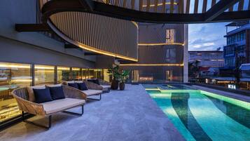 A modern outdoor lounge area with a pool, seating, and a unique architectural design.