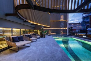 Eine moderne Außenlounge mit Pool, Sitzgelegenheiten und einem außergewöhnlichen architektonischen Design.