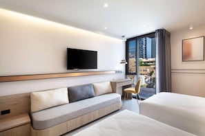 A modern hotel room with a sofa, a bed, a TV, a window with a view of buildings, and a chair. - Best Western Ratchada Hotel (Bangkok)