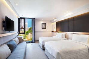 A hotel room with two beds, a sofa, a TV, and a balcony with a city view. - Best Western Ratchada Hotel (Bangkok)