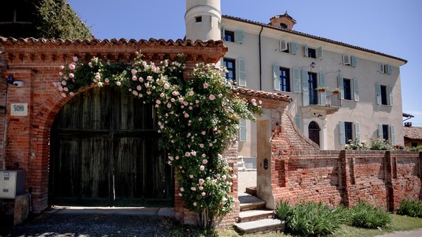 Un edificio tradicional con un gran arco de entrada, una pared de ladrillo y una torre.