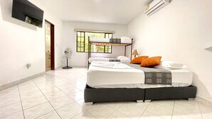 Un dormitorio con una cama nido, una mesita de noche, una lámpara y una ventana con vistas a zonas verdes.
