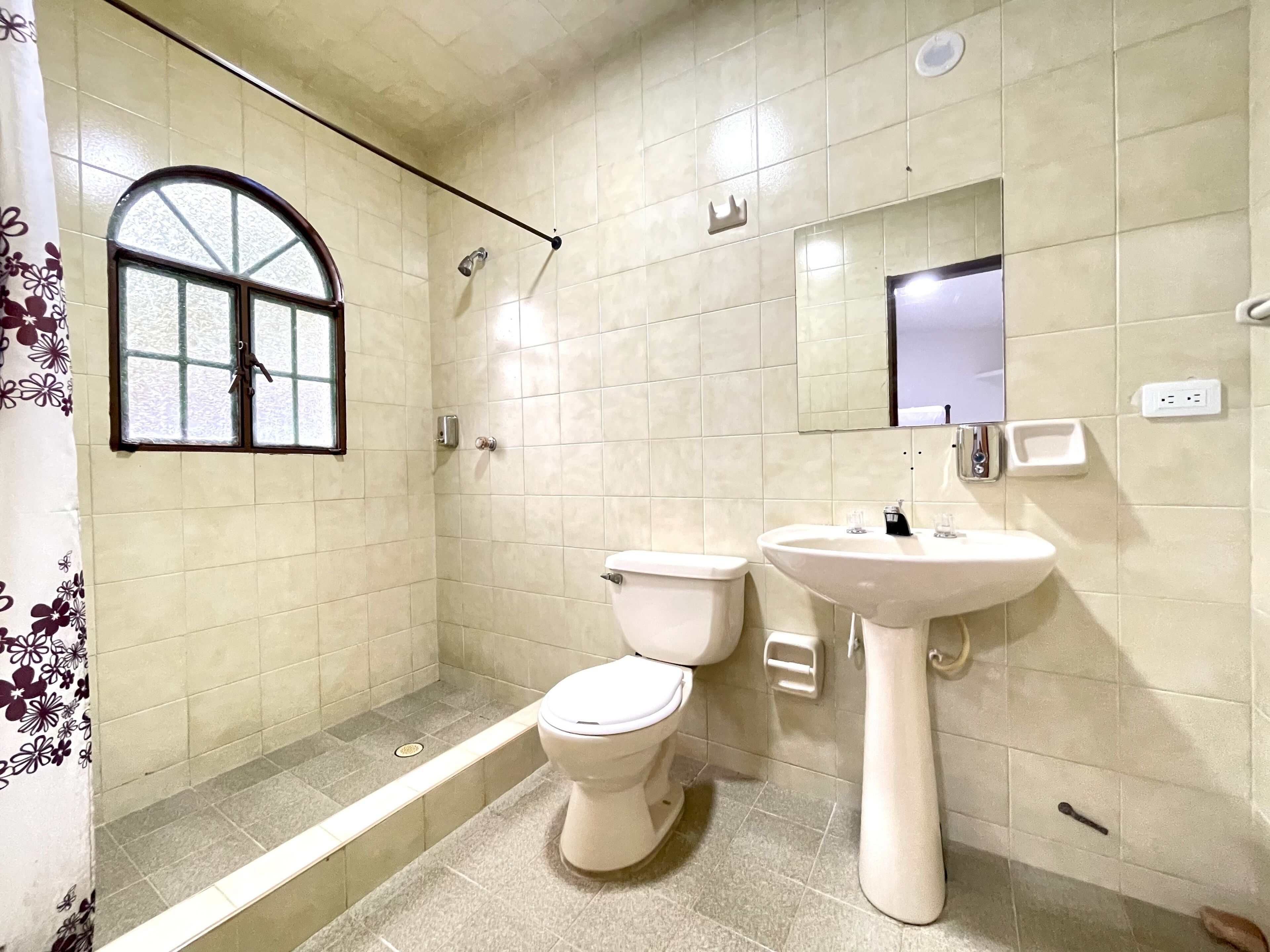 Ein Badezimmer mit Toilette, Waschbecken, Dusche und einem Fenster.