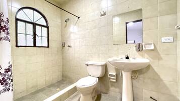 Ein Badezimmer mit Toilette, Waschbecken, Dusche und einem Fenster.