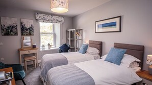 Une chambre avec deux lits, un bureau, une chaise, une armoire et une fenêtre donnant sur un beau paysage.