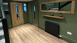 Une pièce spacieuse avec un plancher en bois, un radiateur, un miroir et un escalier.