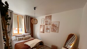 Un dormitorio con cama, mesita de noche, espejo y decoración en la pared.