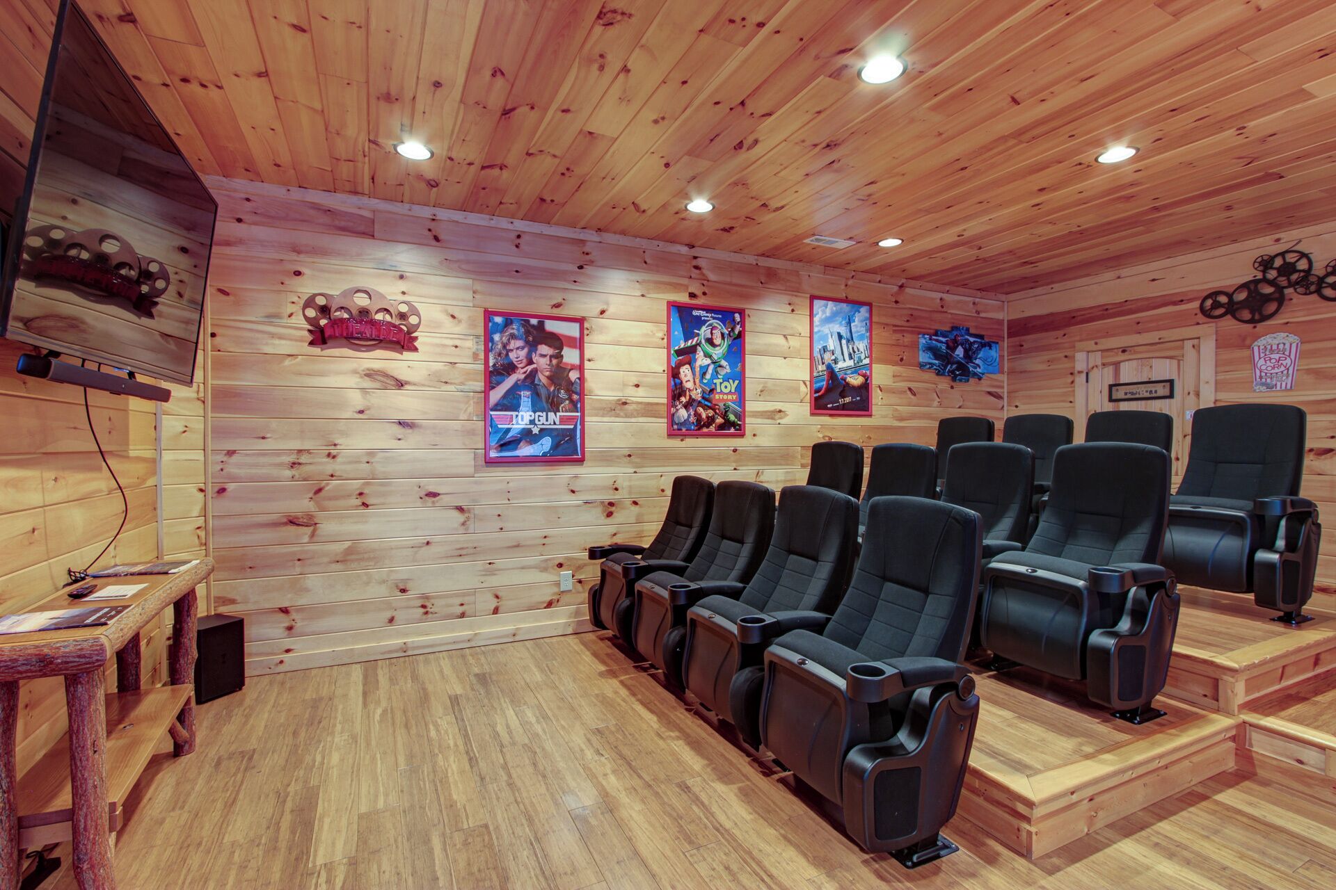 Una stanza con pannelli di legno, sedie nere da teatro, un televisore a sinistra e manifesti cinematografici alle pareti.