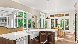A spacious kitchen with a large island, wooden cabinets, and pendant lighting. - Elkhart Lake Oasis - 25 Acres, Hot Tub & Orchard - 15 Min to Road America (Plymouth)