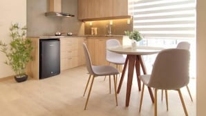 Une cuisine moderne avec des meubles en bois, un réfrigérateur noir et un coin repas comprenant une table ronde et quatre chaises.