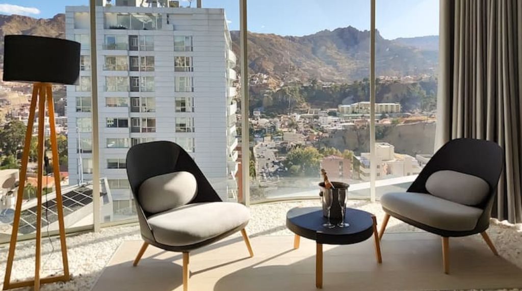 Una habitación moderna con dos sillas, una mesita y un ventanal con vistas a la ciudad.